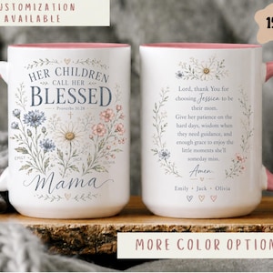 May include: A white 15oz ceramic mug with a pink handle and interior. The front features floral illustrations, the text "Her Children Call Her Blessed", "Proverbs 31:28", "Mama", and names. The back displays a prayer, names, and floral accents.