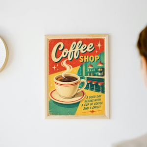 May include: A framed rectangular wall poster featuring a graphic illustration of a steaming cup of coffee on a saucer. The text reads Coffee SHOP and A GOOD DAY BEGINS WITH A CUP OF COFFEE AND A SMILE! The background shows a diner interior.