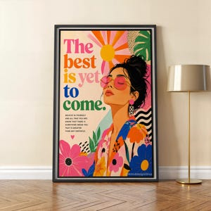 May include: Framed art print with the text "The best is yet to come." The artwork features a woman wearing pink sunglasses, surrounded by colourful flowers and a sunburst design. The print includes the text "Believe in yourself and all that you are."