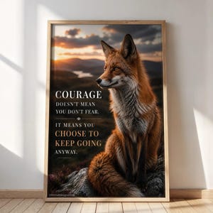 Pode incluir: Uma impressão artística emoldurada apresentando uma raposa vermelha sentada em uma rocha contra uma paisagem ao pôr do sol. O texto diz: COURAGE DOESN'T MEAN YOU DON'T FEAR. IT MEANS YOU CHOOSE TO KEEP GOING ANYWAY. A raposa tem pelo laranja.