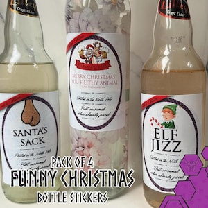May include: Four glass bottles of craft cider with funny Christmas labels. The labels have phrases such as "Santa's Sack" and "Elf Jizz," with festive illustrations. The text "Pack of 4 Funny Christmas Bottle Stickers" is also visible.