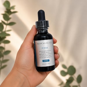 Może przedstawiać: Ciemnoniebieska szklana butelka serum peptydowego przeciwzmarszczkowego Skinceuticals P-Tiox. Butelka ma czarny zakraplacz i białą etykietę z informacjami o produkcie. Butelka zawiera 30 ml serum.