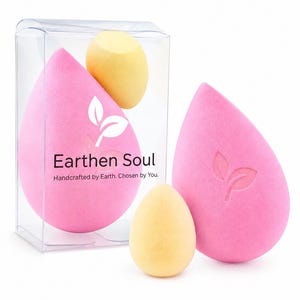 Op de afbeelding: Roze druppelvormige make-upsponzen met een bladlogo en de tekst "Earthen Soul". Twee gele eivormige sponzen zijn ook zichtbaar. De sponzen zijn verpakt in een doorzichtige plastic doos. De tekst "Handcrafted by Earth. Chosen by You." is ook zichtbaar.