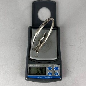 May include: A silver bracelet with a decorative design is placed on a digital scale. The scale displays a weight of 32.0. The scale is a Salter Brecknell PB-500 model.