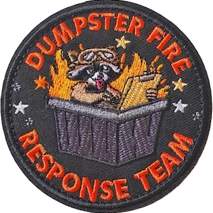 May include: Embroidered patch with the words "DUMPSTER FIRE RESPONSE TEAM" in orange on a black background. The patch features a raccoon wearing goggles in a burning dumpster, holding a clipboard. Stars are scattered around the design.