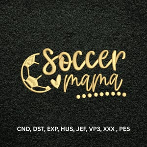 Könnte beinhalten: Ein Stickmuster mit dem goldfarbenen Schriftzug soccer mama, einem stilisierten Fußball und einem kleinen Herz. Unter dem Text sind die Dateiformate CND, DST, EXP, HUS, JEF, VP3, XXX und PES in Weiß auf schwarzem, strukturiertem Grund.