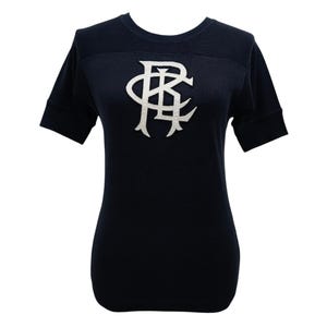May include: Navy blue short-sleeve shirt with a white, stylized logo on the chest. The shirt has a crew neck and a fitted silhouette. The logo appears to be a monogram or emblem.
