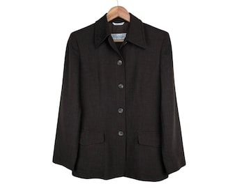 Puede incluir: Una blazer marrón oscuro con solapas, dos bolsillos delanteros y cierre de botones. La blazer está colgada en una percha de madera sobre un fondo blanco. La etiqueta dice "Max Mara".