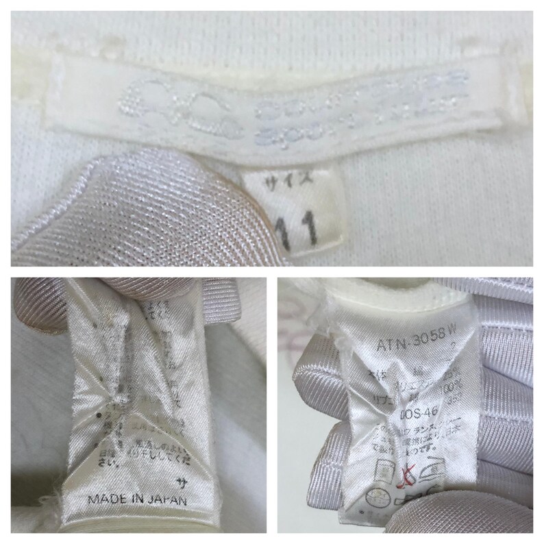 以下が含まれることがあります： 「MADE IN JAPAN」と記された白い衣類タグと、サイズ「11」が記載されたタグ。モデル番号「ATN-3058 W」や、アイロン禁止マークを含む様々な洗濯表示が記載された追加のケアラベルが確認できます。