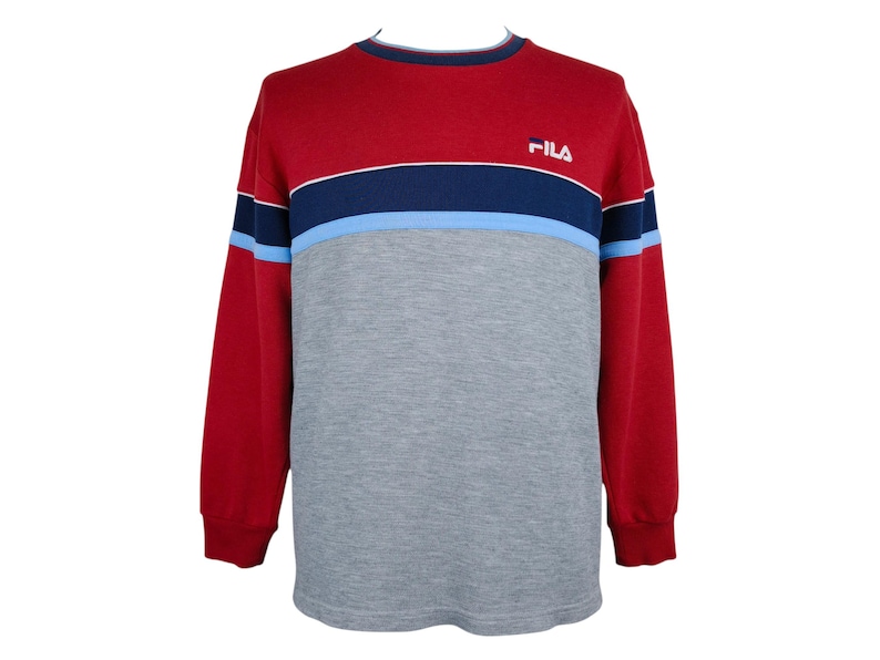 Puede incluir: Una sudadera de manga larga roja, azul marino, azul claro y gris. La parte superior es roja, con una franja azul marino y azul claro en el pecho. La mitad inferior es gris. El logotipo de Fila est&aacute; en la parte superior del pecho.