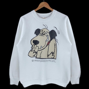 Puede incluir: Sudadera blanca con un dibujo animado de un perro. El perro es de color marrón claro con orejas negras y una lengua roja, mostrando una expresión traviesa. El texto "©HANNA-BARBERA PROD.INC." está impreso debajo. La sudadera tiene mangas largas.