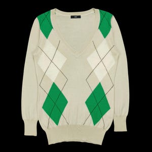 Könnte beinhalten: Beiger V-Ausschnitt-Pullover mit grünem, weißem und schwarzem Rautenmuster. Der langärmlige Pullover hat gerippte Bündchen und Saum. Der Pullover ist aus einem weichen, bequemen Material.