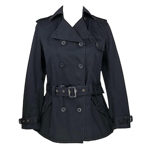 Könnte beinhalten: Ein schwarzer Trenchcoat mit doppelreihigem Design, Gürtel in der Taille und geknöpften Manschetten. Der Mantel hat einen klassischen Kragen und Schulterklappen und bietet einen zeitlosen Stil.
