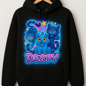 May include: Black hoodie with a colourful graphic of three cartoon cats in blue hues, with stars. The word "DERPY" is written below the cats. The hoodie has a drawstring hood and a kangaroo pocket. The design is suitable for casual wear.