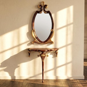 May include: An oval-shaped mirror with a dark brown frame and gold accents hangs above a matching console table. The mirror and table have ornate, classic designs. The table has a single leg and is made of dark brown wood with gold detailing.