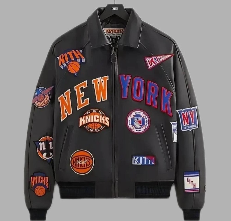 Puede incluir: Chaqueta de cuero negra con m&uacute;ltiples parches con balones de baloncesto y las palabras "NEW YORK" en naranja y azul. La chaqueta tiene un estilo bomber, con cuello y cierre de cremallera.