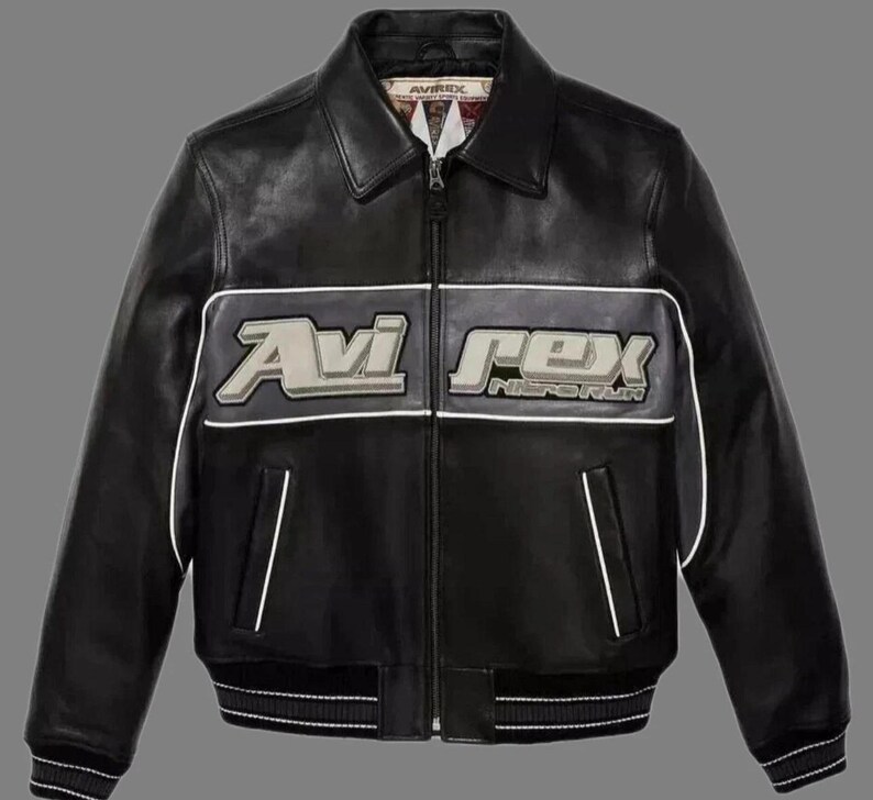 May include: Black leather jacket with the "Avi Rex" logo in white and gray across the chest. The jacket has a ribbed hem and cuffs, a zipper closure, and white trim. A classic bomber jacket style.