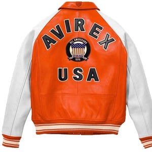 May include: Orange and white leather jacket with the word "AVIREX" across the back. The jacket has a patch with the words "ALL AMERICANS" and "USA" below it. The sleeves are white, and the cuffs and hem have striped detailing.