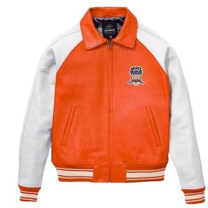 May include: Orange and white leather jacket with a zip-up front and a collared neckline. The jacket features white sleeves and a striped hem and cuffs. An emblem is stitched on the chest. The brand name "AVIREX" is visible on the label.