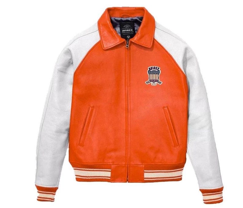May include: Orange and white leather jacket with a zip-up front and a collared neckline. The jacket features white sleeves and a striped hem and cuffs. An emblem is stitched on the chest. The brand name "AVIREX" is visible on the label.
