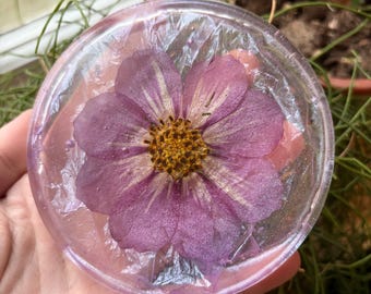 Ett par underlägg med texturerat tygmönster och blommotiv i harts