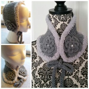 Puede incluir: Un cuello de punto de ganchillo gris con un ribete blanco peludo y dos flores de ganchillo grises con centros de perlas. El cuello tiene una corbata de ganchillo gris.