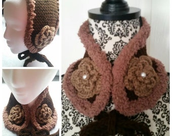 May include: A brown crocheted hat and matching neck warmer with brown and pink flowers. The hat has a wide brim and the neck warmer has a tie.