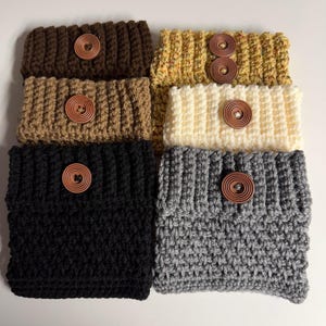 May include: A white ceramic mug with a black handle and the text "But First, Coffee" in a handwritten style. The mug is on a white surface. The mug is approximately 4 inches tall.