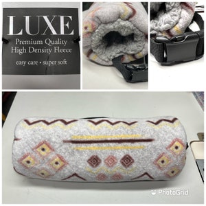 Könnte beinhalten: Eine graue und weiße Fleece-Decke mit geometrischem Muster. Die Decke ist aufgerollt und hat einen schwarzen Gurt mit einer Schnalle. Das Etikett auf der Decke lautet "LUXE Premium Quality High Density Fleece easy care - super soft".