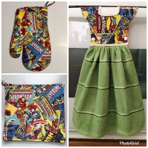 Puede incluir: Un juego de toallas de cocina con temática de cómics. El juego incluye una toalla de té verde con ribete blanco y un guante para horno y una agarradera a juego. La tela presenta un collage de portadas de cómics con personajes como Iron Man, Wolverine y Spider-Man.