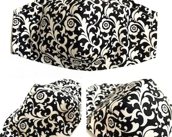 May include: Black and white face mask with a floral pattern. The mask is made of fabric and has a 3D shape.