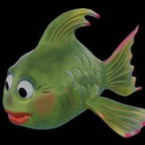 Op de afbeelding: Een grillige groene visfiguur met grote, expressieve ogen, roze wangen en rode lippen. De vinnen en staart zijn geaccentueerd met roze. De vis heeft een cartoonachtig ontwerp en staat tegen een zwarte achtergrond.