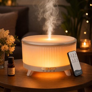 May include: A white cylindrical essential oil diffuser with a ribbed exterior and a warm glowing light, emitting a steady stream of mist. It features buttons labeled LIGHT and MIST, with timer settings for 1H, 3H, 6H, and ON, accompanied by a remote control.
