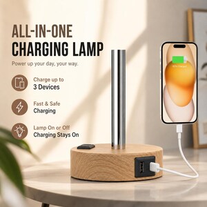 May include: An all-in-one charging lamp with a round, light-wood grain base featuring a central metallic cylindrical post. The base includes a USB port with a connected white charging cable plugged into a smartphone displaying a battery icon.