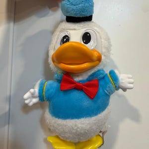 May include: A white ceramic mug with a black handle and the text "But First, Coffee" in a black, handwritten-style font. The mug is on a white surface.