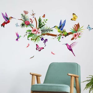 May include: A wall decal featuring a watercolor design of hummingbirds, butterflies, flowers, and foliage. The birds are depicted in vibrant colors, with pink, purple, red, and blue hues. The butterflies are yellow and pink. The floral elements include pink and white blossoms.