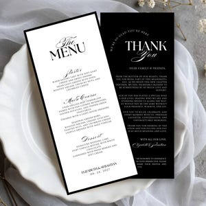 Może przedstawiać: Biały ceramiczny kubek z czarnym uchwytem i napisem "But First, Coffee" czarną, odręczną czcionką. Kubek stoi na białej powierzchni.