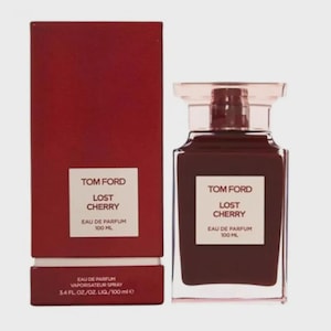 May include: A Tom Ford Lost Cherry Eau de Parfum bottle and box. The bottle is a dark red square shape with a clear top. The box is a matching dark red with white labels. The labels read "Tom Ford Lost Cherry Eau de Parfum 100 ML".