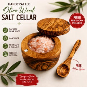 May include: A round olive wood salt cellar with a matching lid, filled with pink Himalayan salt crystals. A small olive wood spoon is placed next to the cellar. The image includes text: HANDCRAFTED Olive Wood SALT CELLAR, FREE MINI SPOON INCLUDED.