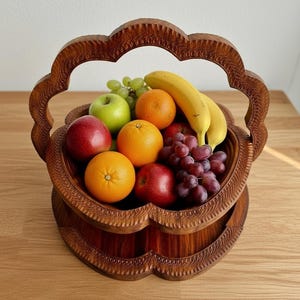 May include: A carved wooden fruit basket filled with fresh fruit. The basket is made of dark brown wood and has a decorative, scalloped edge. The fruit includes oranges, apples, grapes, and bananas.