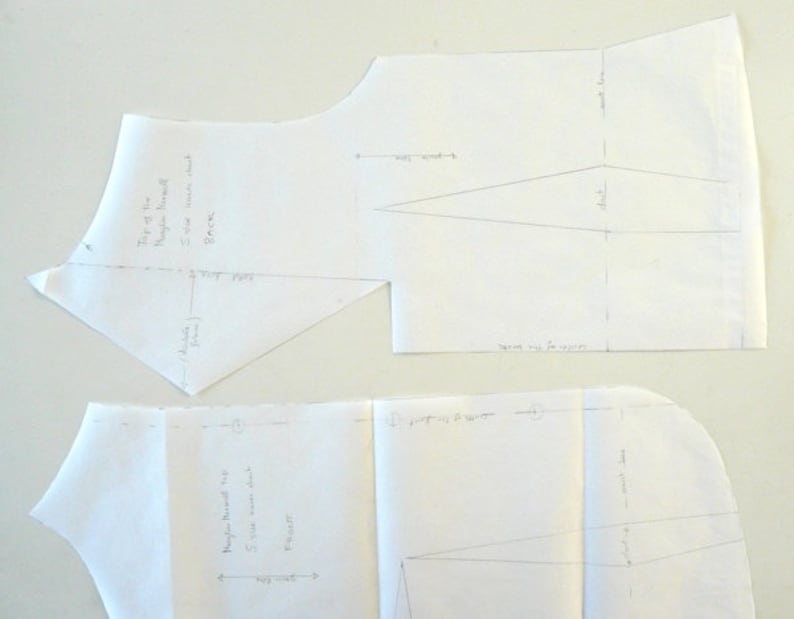 May include: Two white paper sewing patterns with handwritten notes and diagrams. The top pattern is labeled "Back" and the bottom pattern is labeled "Front". The patterns are for a top or dress.
