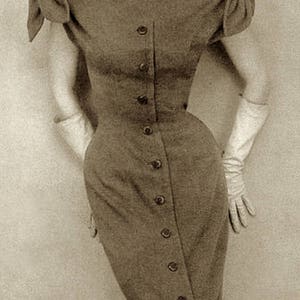 May include: A vintage-style dress with a button-down front and a fitted silhouette. The dress is a muted brown color and features short sleeves with a bow detail. A wide-brimmed hat and white gloves complete the ensemble.