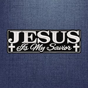 May include: A rectangular black embroidered patch featuring the white text JESUS Is My Savior in a combination of bold serif and script fonts. The design includes a small white cross on both the left and right sides of the text.