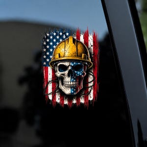 May include: A decal featuring a human skull wearing a yellow hard hat, positioned over a distressed American flag background. The skull is partially colored with red, white, and blue star patterns, and the entire design has a weathered, brush-stroke effect.