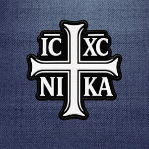 May include: A black and white embroidered patch featuring a central cross design. The white cross is outlined in black and contains the white text IC XC NI KA arranged in the four quadrants. The patch has a thick black border.