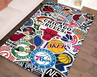 May include: Rectangular rug with a collage of NBA team logos. The rug features logos for the Chicago Bulls, Los Angeles Lakers, Boston Celtics, and other teams. The design incorporates red, white, blue, and yellow colours.