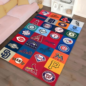 May include: A rectangular area rug featuring a patchwork design with logos of various Major League Baseball teams. The rug has a colorful arrangement of squares, each displaying a team's logo in vibrant colors. The rug is placed on a wooden floor.