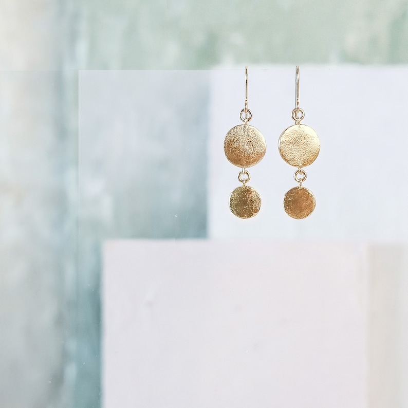 May include: Gold dangle earrings with two round discs on each earring.