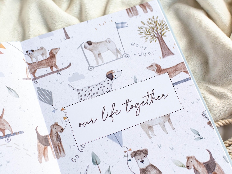 May include: An open book with a light blue and white patterned cover featuring watercolor illustrations of dogs on skateboards, scooters, and kites. The text "our life together" is displayed in a cursive font.