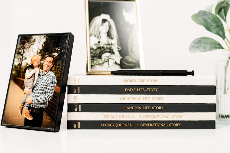May include: A stack of black and white journals with gold lettering. The titles of the journals are "Mom's Life Story", "Dad's Life Story", "Grandma's Life Story", "Grandpa's Life Story", "Legacy Journal | A Generational Story", and "Legacy Journal | A Generational Story".